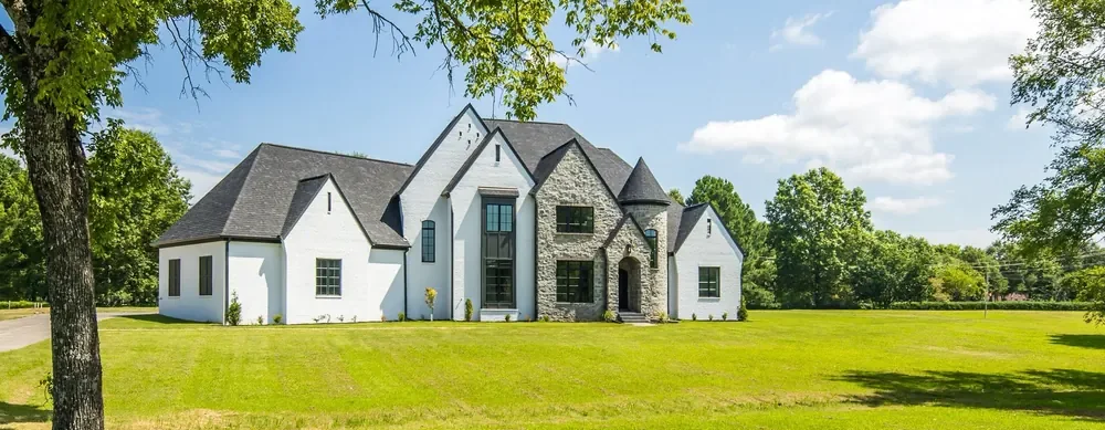 A finished home across an open lawn, framed by an oak