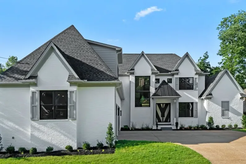 A completed home, white brick with a dark roof