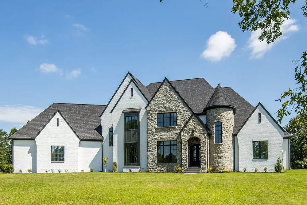 A completed home, white with stone and a turret