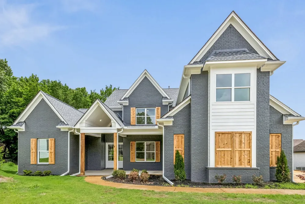 A completed home, grey brick with cedar shutters