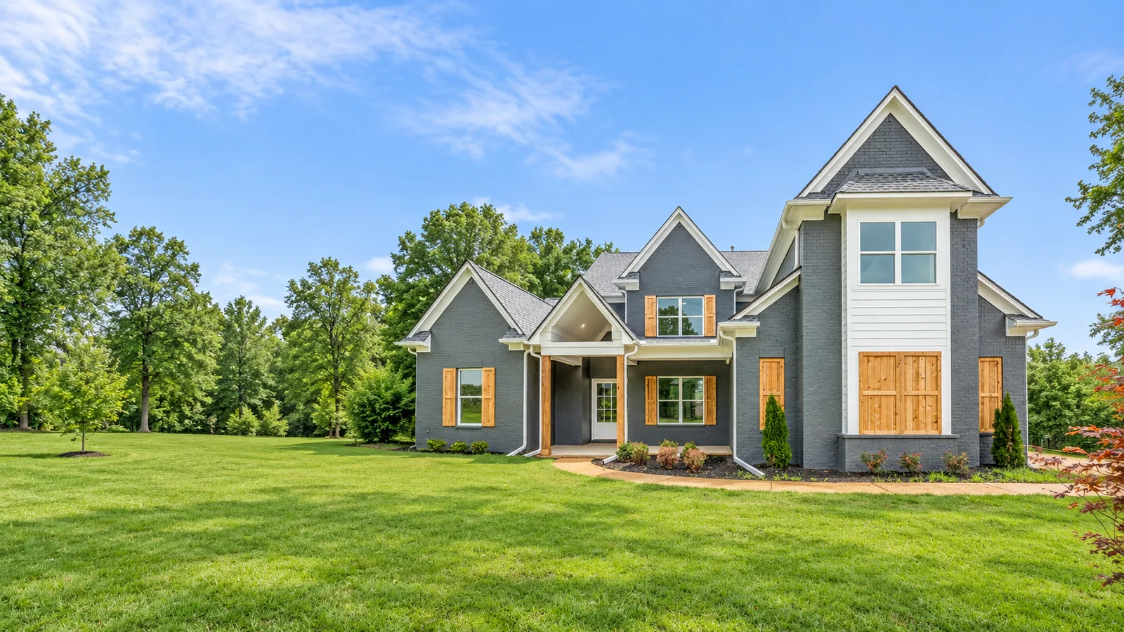 A finished home in grey brick with cedar shutters, seen across the front lawn